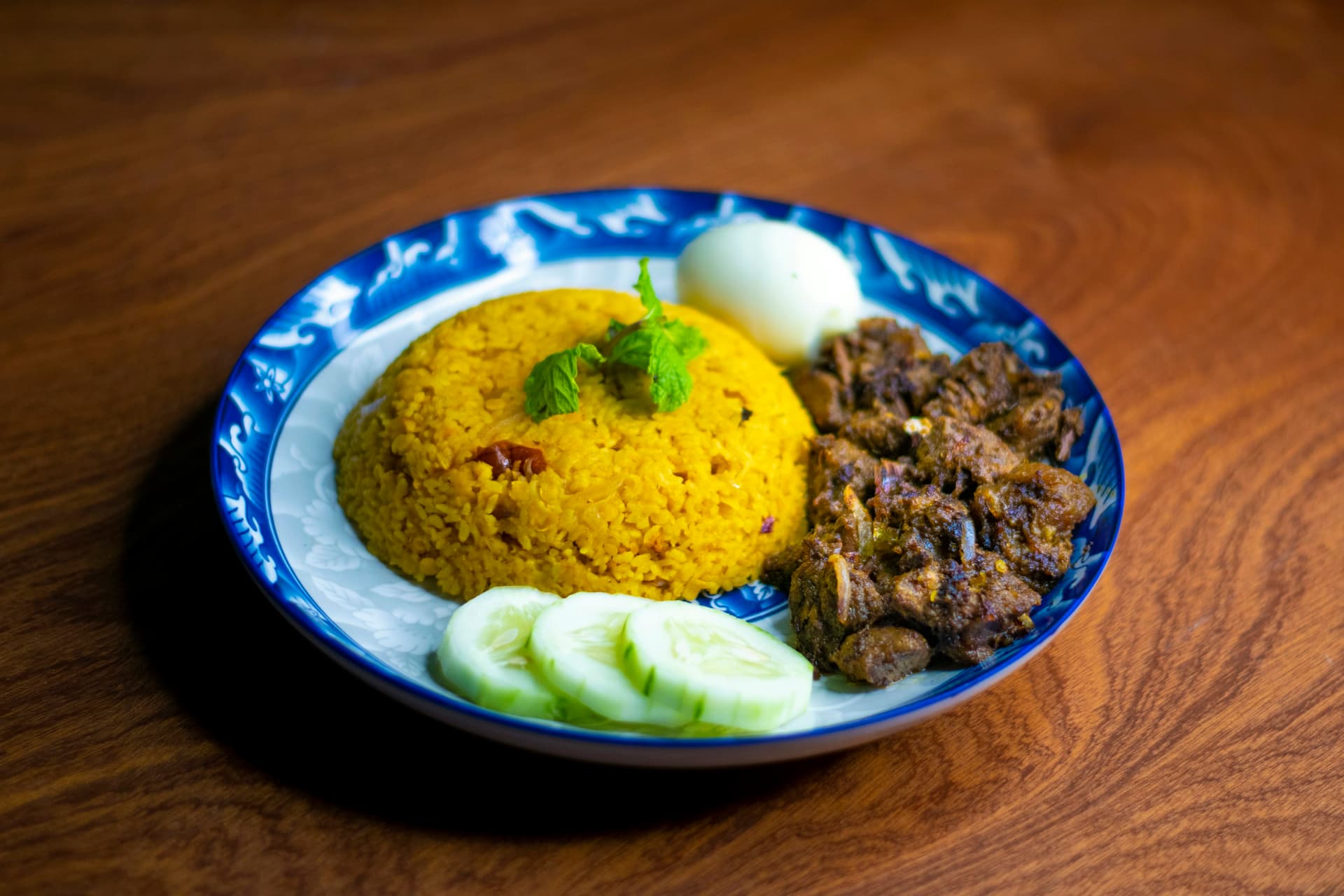 A colourful plate of Bangladeshi biryani served with accompaniments