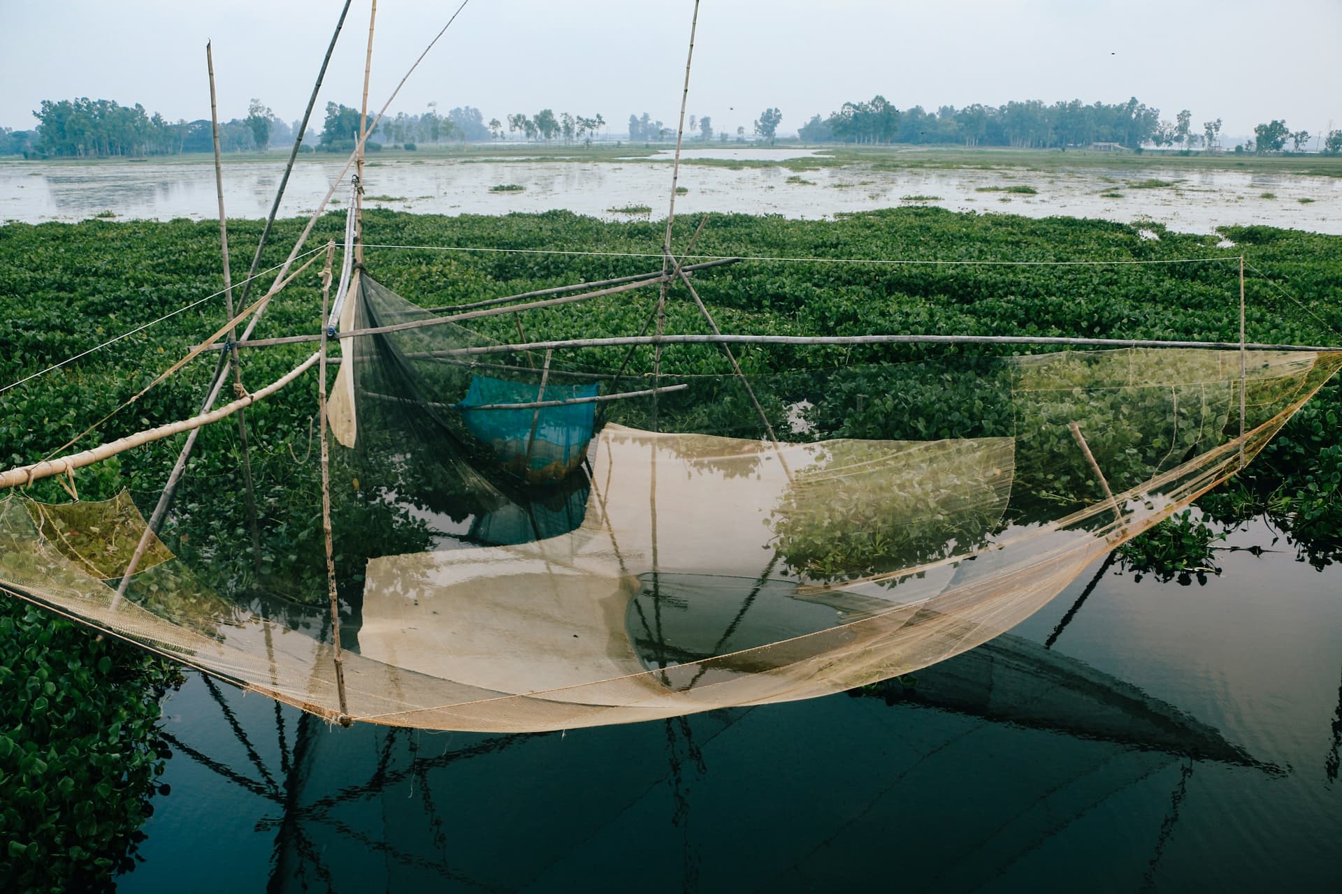 A small boat and fishing net on a quiet river in Naogaon