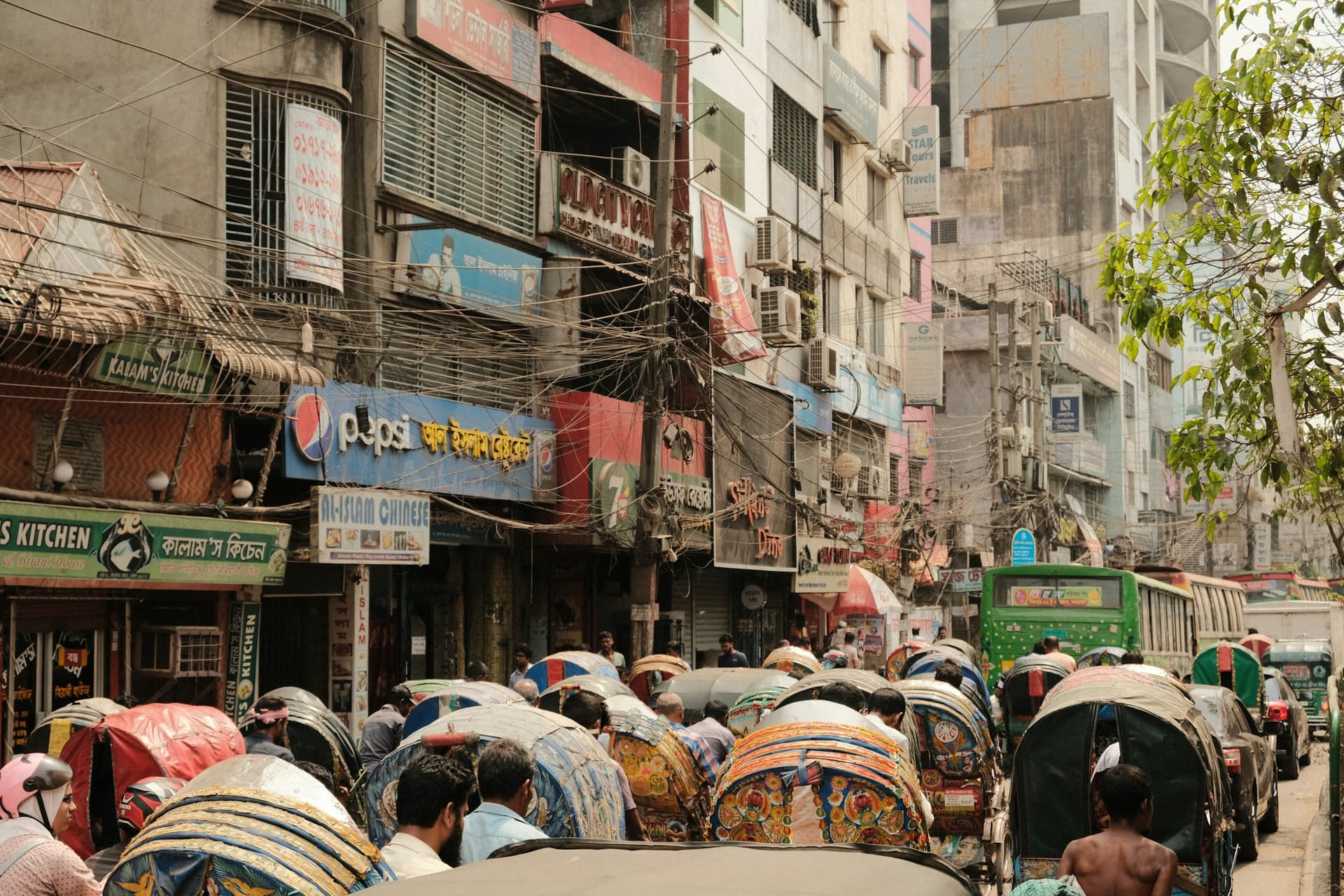 People walking beneath umbrellas on a busy street in Dhaka