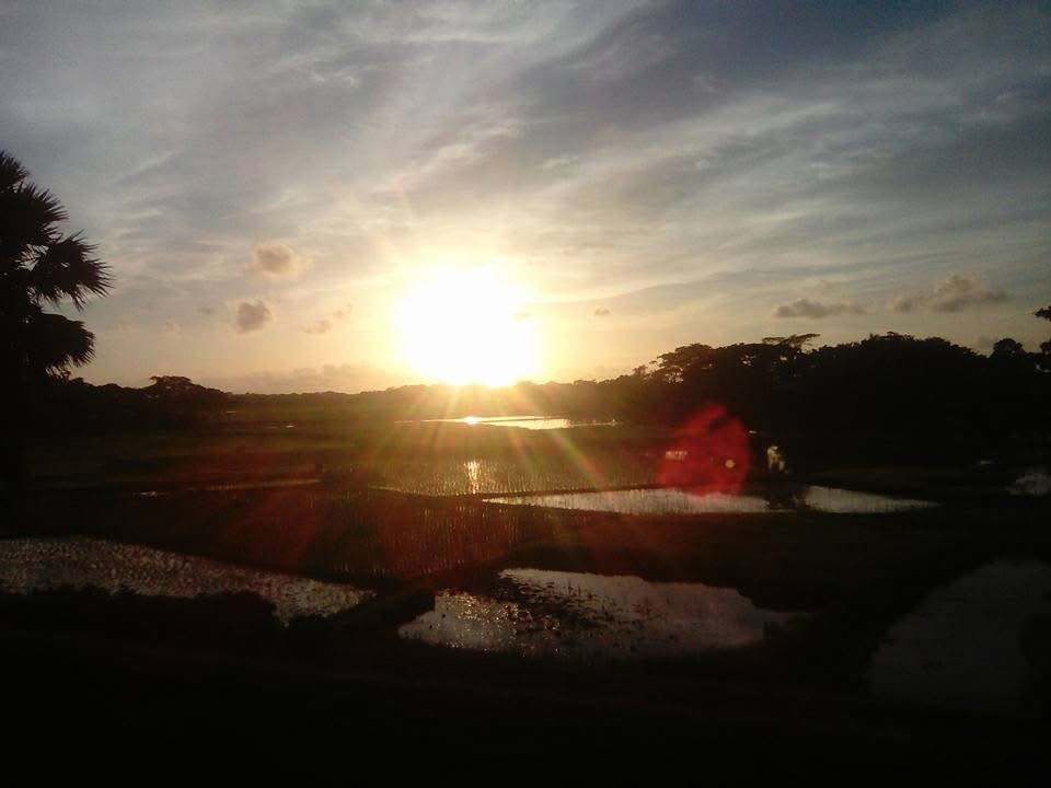 A rural road leading toward the setting sun