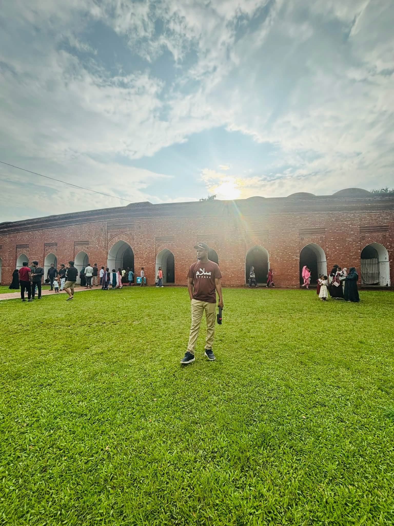 A person walking through a green field beneath a bright sky