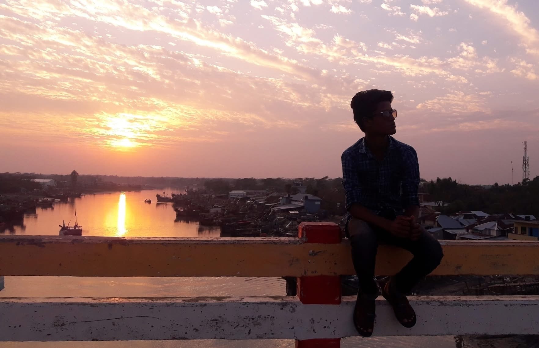 A seated figure watching the sunset from a rooftop