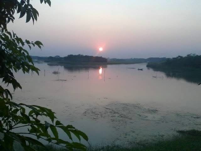A lone figure standing beside a river at dusk