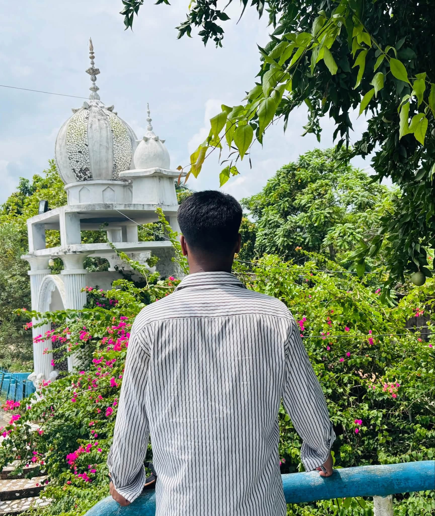 A white mosque seen through leafy greenery
